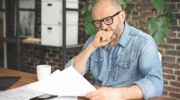 mature adult man working from office ( with laptop, paperwork, Negative Emotion)