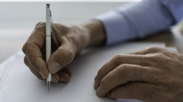 A hand with a pen signing some documents.