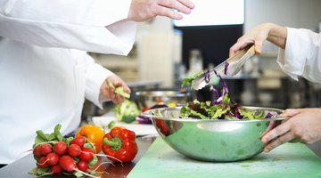 Chefs preparing salad in kitchen, mid section