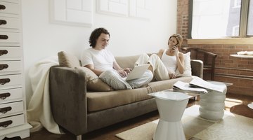 Young adult couple using laptop computer and cell phone