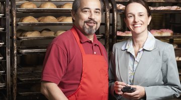Portrait of a businesswoman smiling with a male baker in a bakery